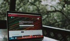 pexels-photo-18096282-18096282 Open laptop showing a website screen on a wooden table in an outdoor terrace setting.