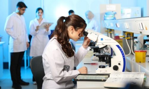 pexels-photo-32213405-32213405 Young female scientist examining samples under a microscope in a modern laboratory setting.