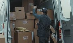 pexels-photo-6169060-6169060 A courier organizing boxes in a delivery van for shipment on a cloudy day.